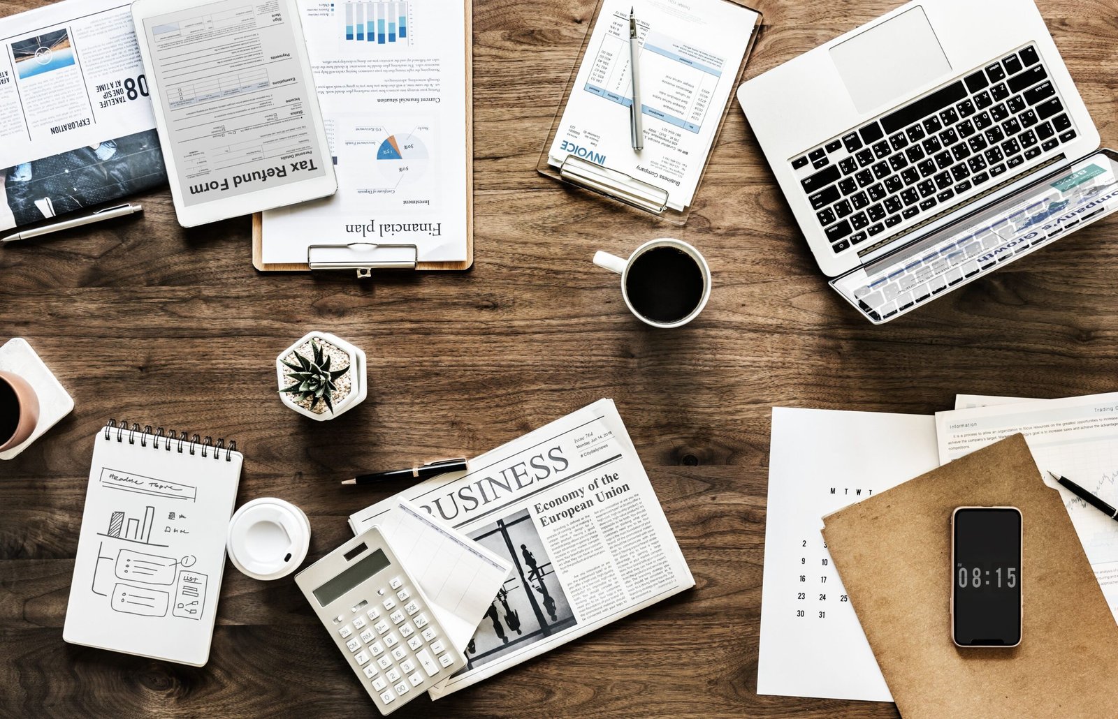 Digital marketing workspace with laptop, documents, and business planning tools on desk